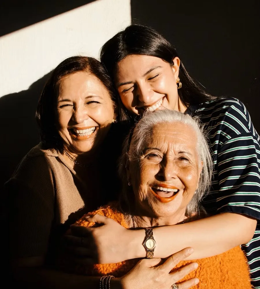 A grandmother laughing with her daughter and granddaughter